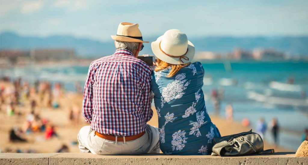 Pareja de personas mayores sentadas en un banco mirando el mar en un excusrión del IMSERSO | Sevilla Senior